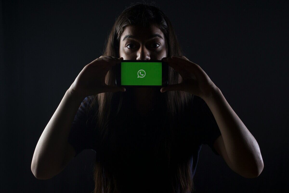 ragazza tiene in mano cellulare con schermata WhatsApp